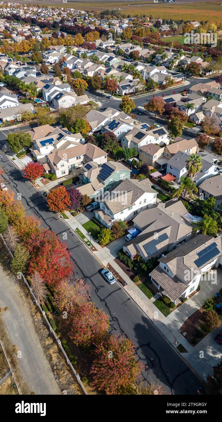 Vertical Photo of houses in a neighborhood with solar panels and beautiful fall color trees in California Stock Photo