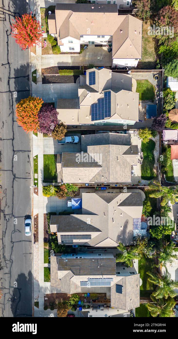 Vertical Photo of houses in a neighborhood with solar panels and beautiful fall color trees in California Stock Photo