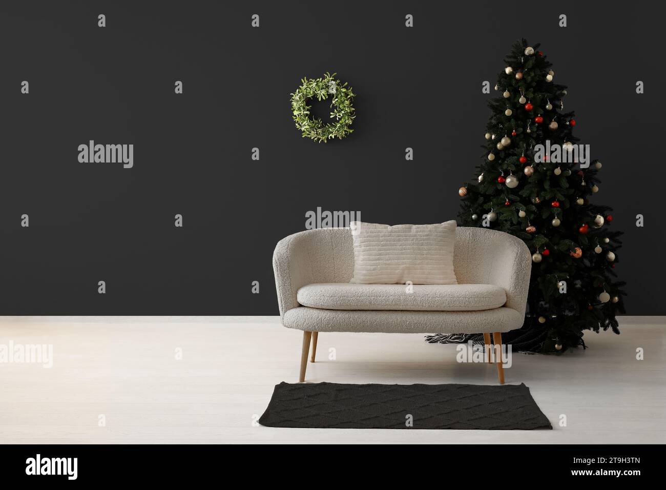 Beautiful Christmas tree with comfortable sofa near dark wall. Banner for design Stock Photo