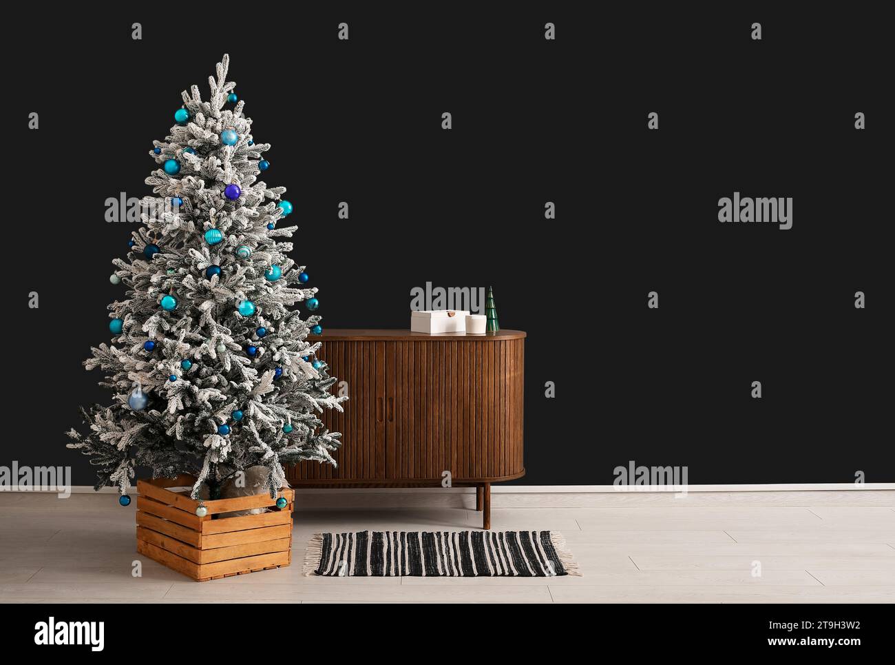 Beautiful Christmas tree with wooden dresser near dark wall. Banner for design Stock Photo