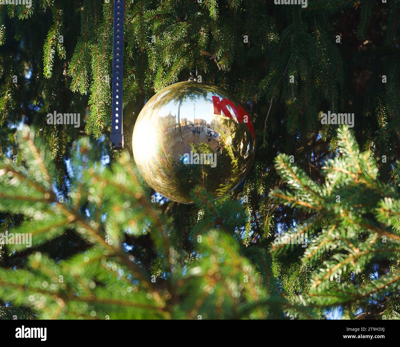 Christmas bauble on a christmas tree, reflecting the town square below. Stock Photo