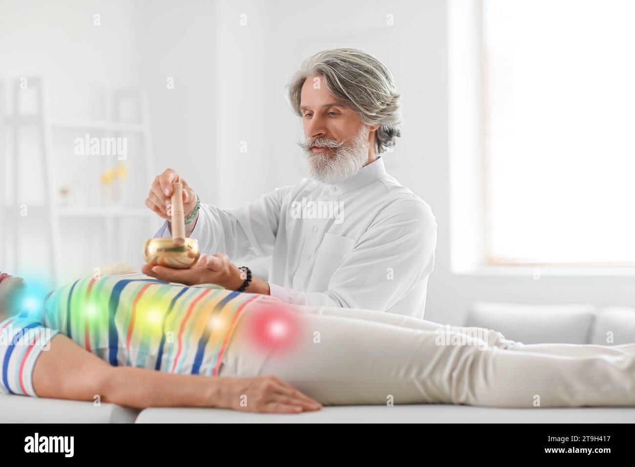 Male Reiki master with Tibetan singing bowl healing patient Stock Photo