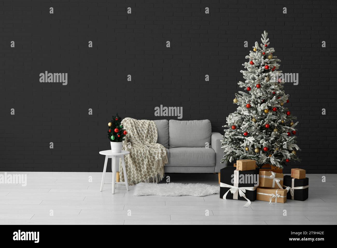 Beautiful Christmas tree with gifts and comfortable sofa near dark wall. Banner for design Stock Photo