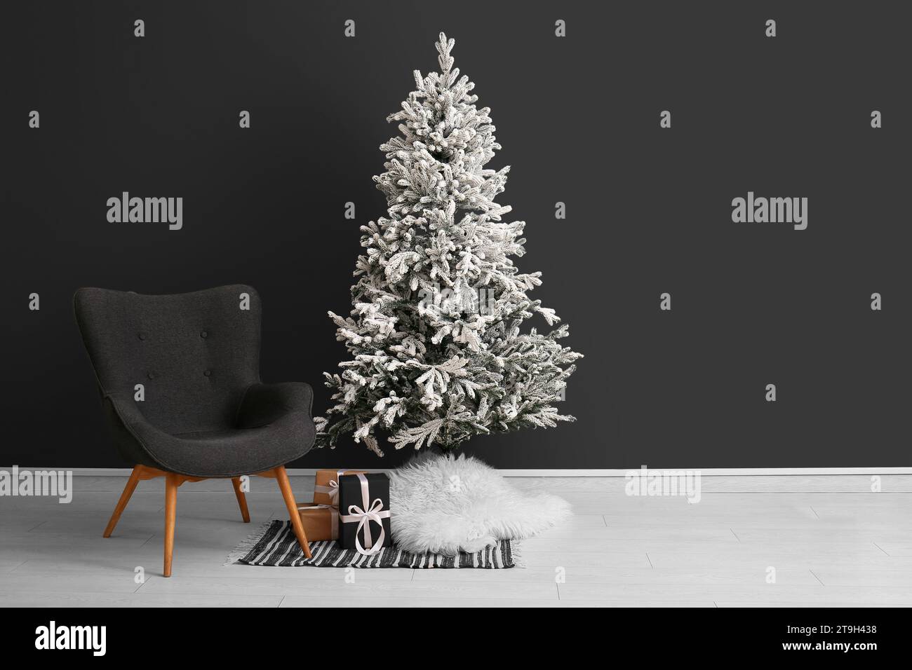 Beautiful Christmas tree with comfortable armchair near dark wall. Banner for design Stock Photo