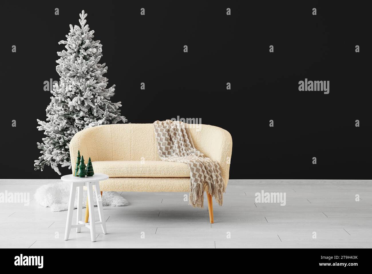 Beautiful Christmas tree with comfortable sofa and table near dark wall. Banner for design Stock Photo