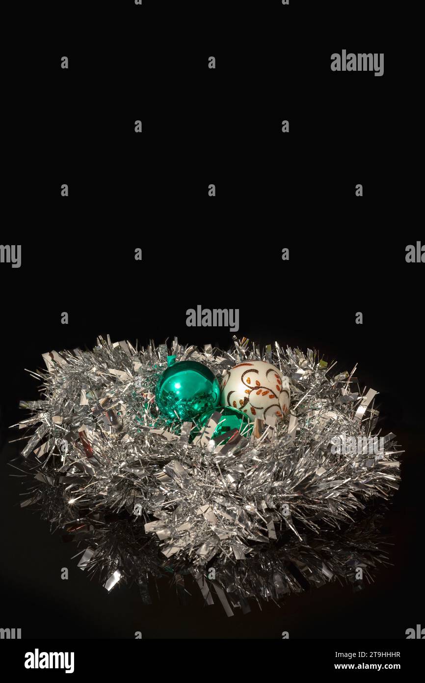White and green Christmas baubles nested in a silver Christmas tinsel ...