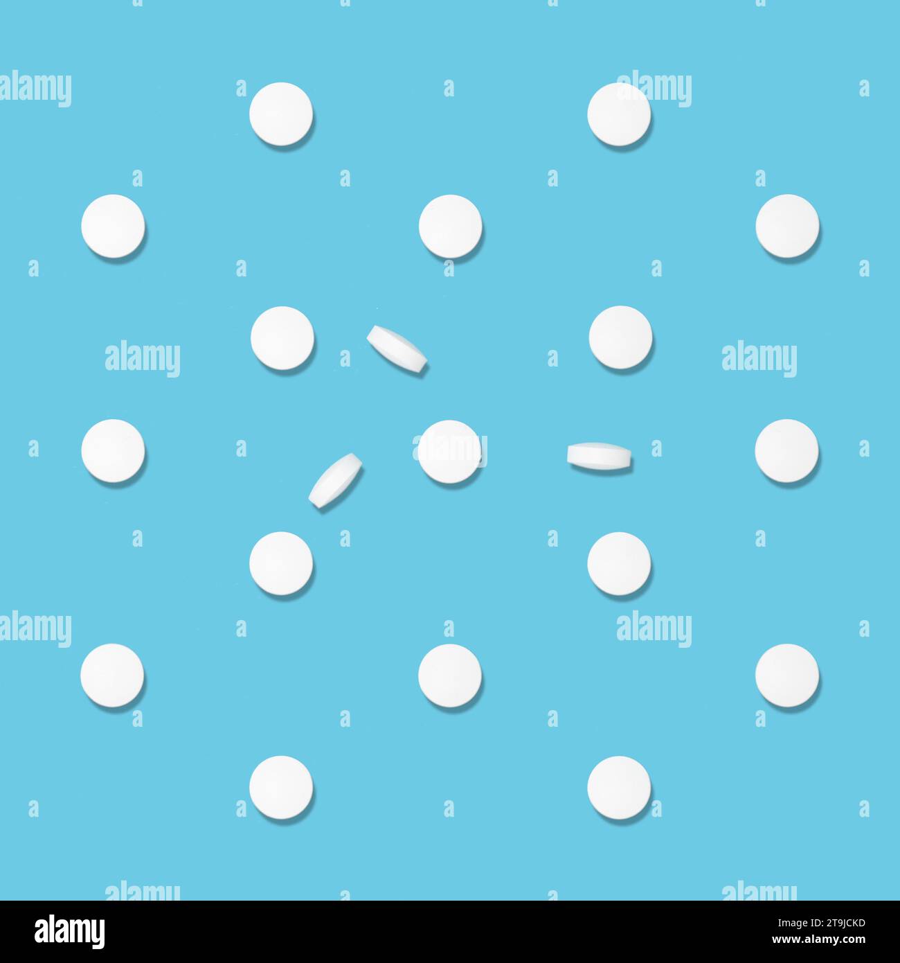 White tablets pattern in hard light on soft light blue color, top view. Medical and pharmacy remedies, home medicine chest. Stock Photo