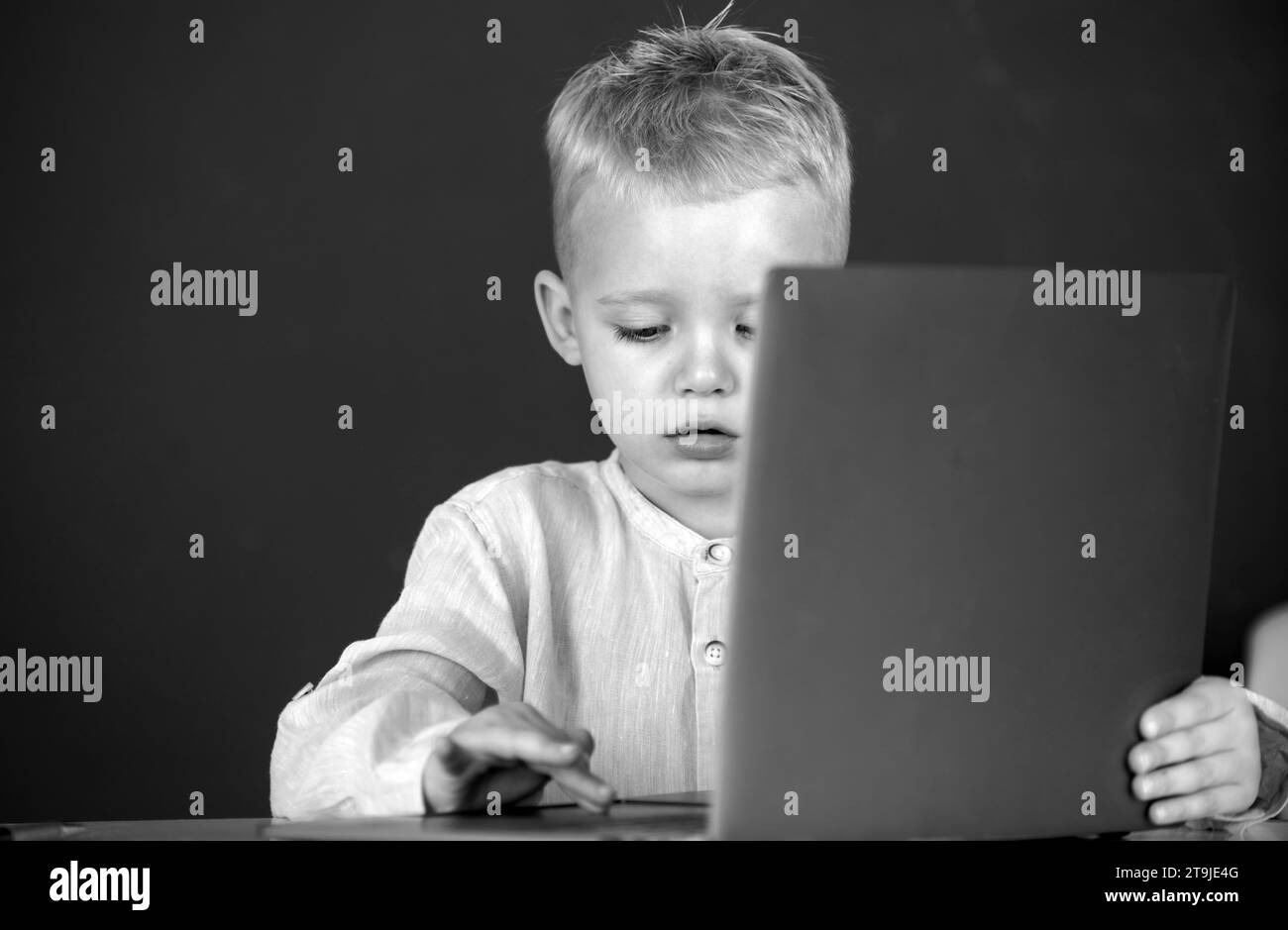 School child using digital pc laptop in class. Portrait of funny pupil of primary school study programming. Cute pupil face closeup on blackboard Stock Photo