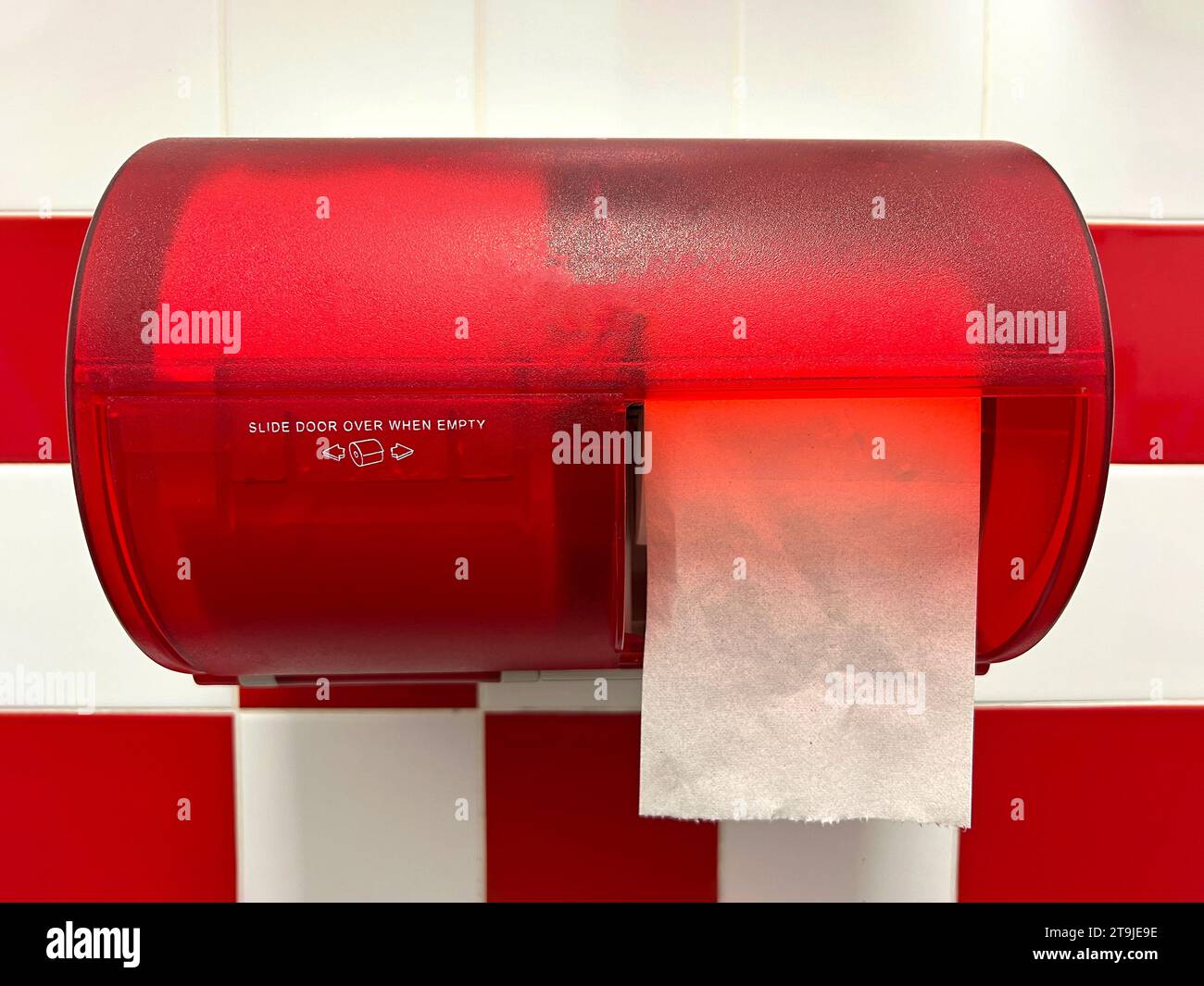 Transparent red toilet paper dispenser with two rolls. One hanging down