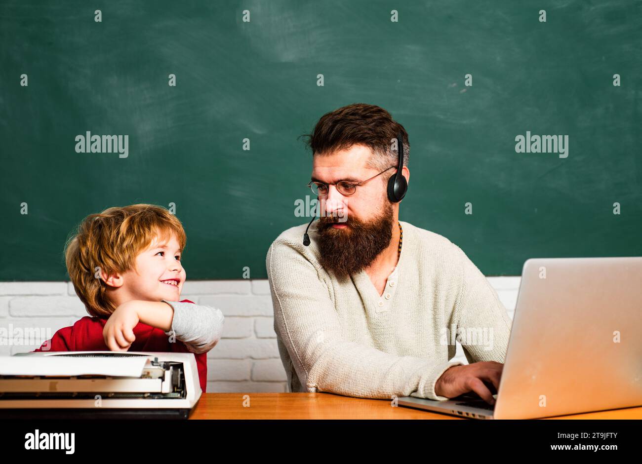 Man teacher play with preschooler child. Back to school. Tutoring. Man teaches child. Daddy and son together. Teacher helping pupils studying on desks Stock Photo