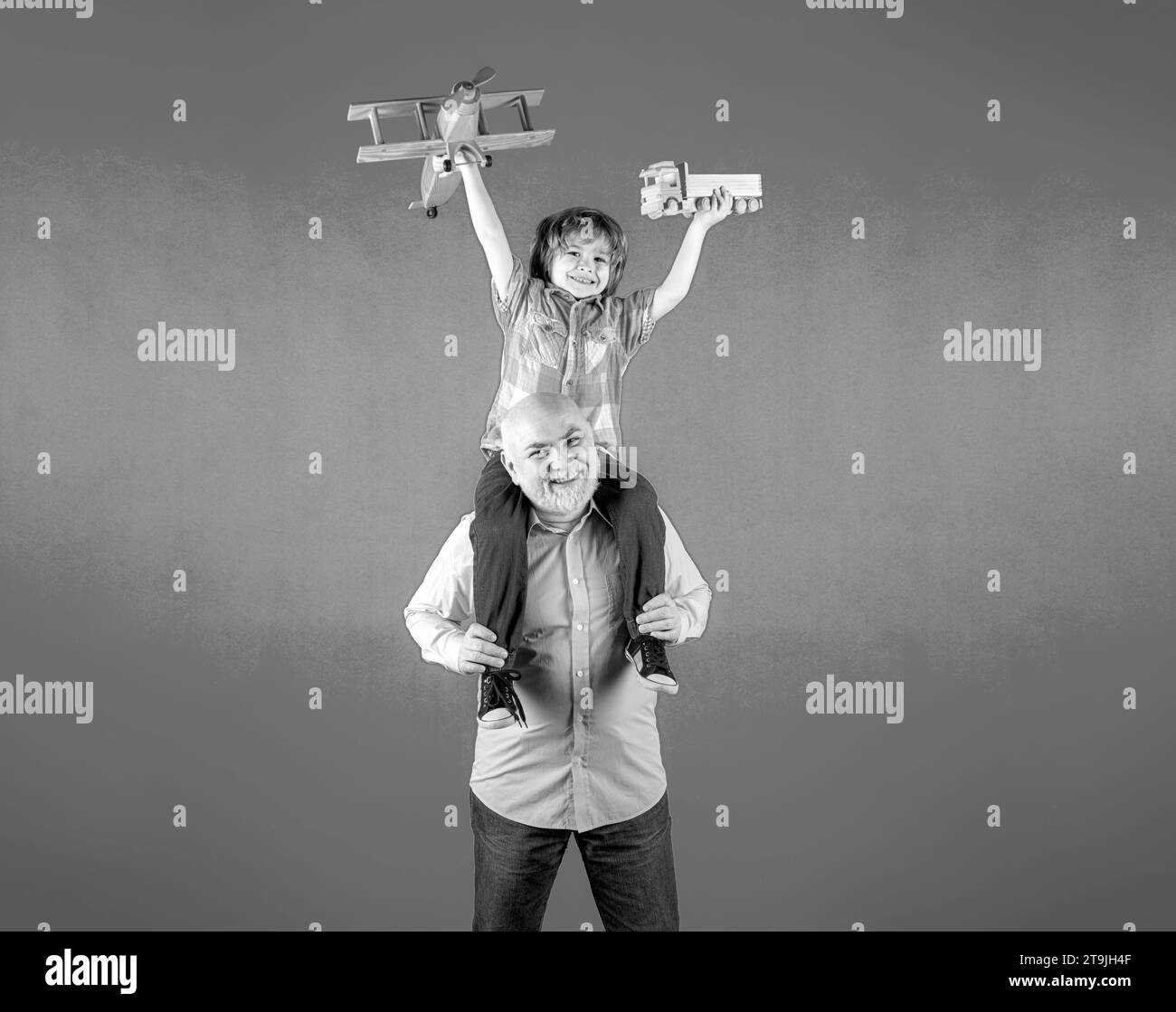 Grandfather and grandson piggyback ride with plane and wooden toy truck