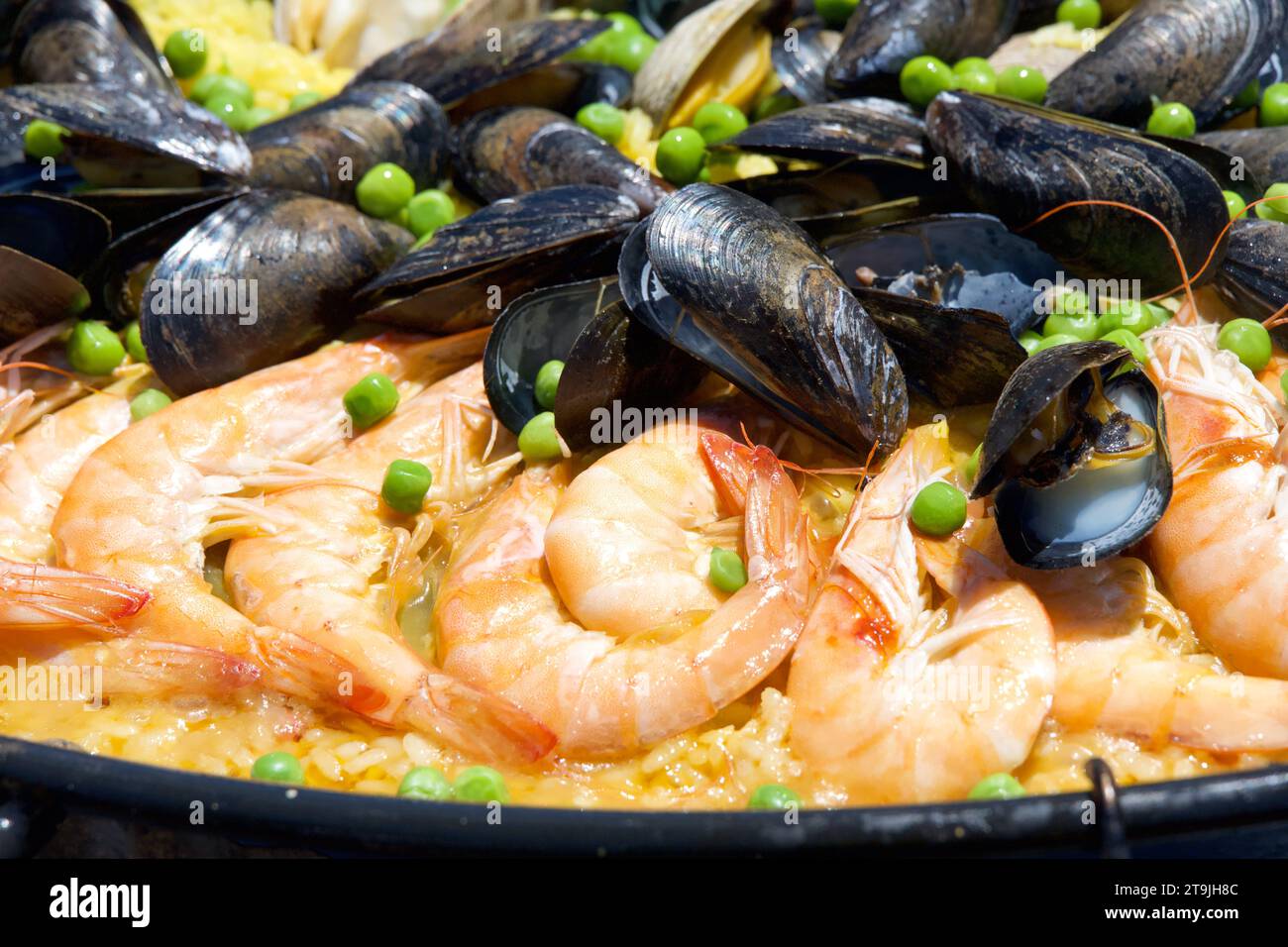 Close up on clams, muscles, shrimp rice and peas cooking in a giant outdoor wok. traditional Paella Stock Photo