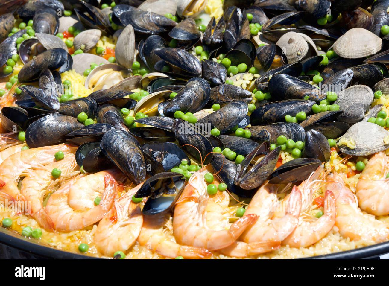 Close up on clams, muscles, shrimp rice and peas cooking in a giant outdoor wok. traditional Paella Stock Photo