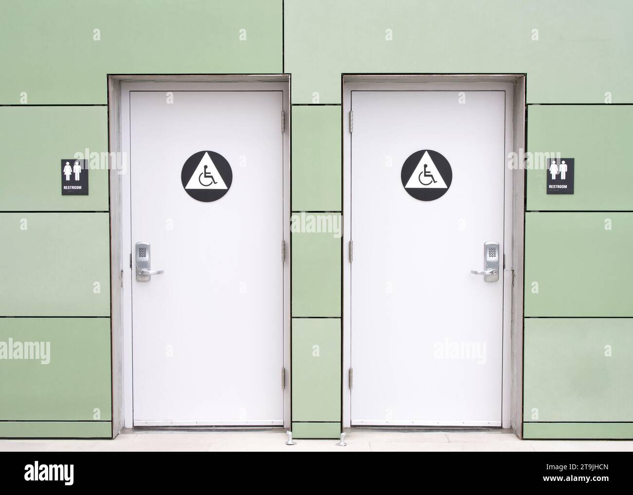 Public bathroom doors on outside building, concrete walkway. Unisex toilets with keypad locks on doors. Stock Photo