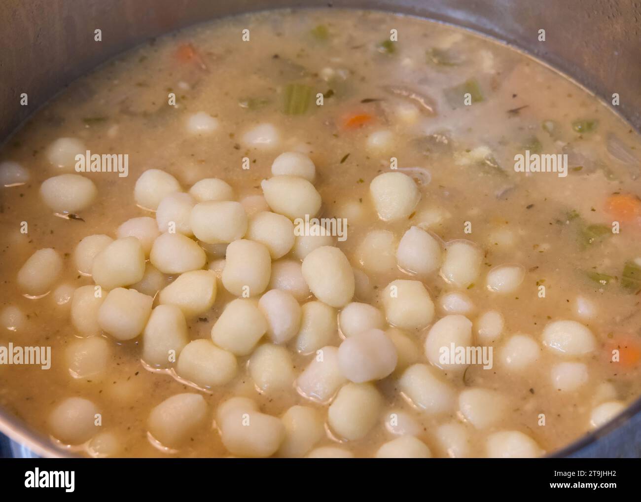 Top view of a large pot full of chicken gnocchi stew cooking on stove top. Stock Photo