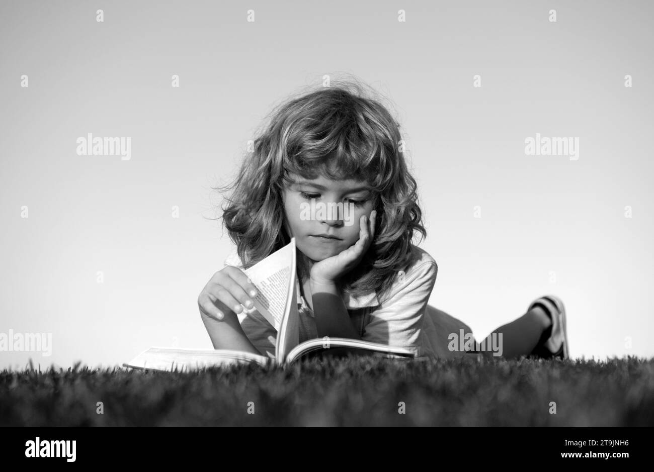 Smart kid boy reading book in park outdoors Stock Photo Alamy
