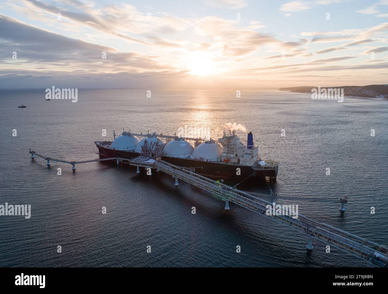 Aerial of Liquified Natural Gas LNG carrier moored to a small gas terminal. Fuel crisis. Sanctions. Wide panoramic shot. Stock Photo