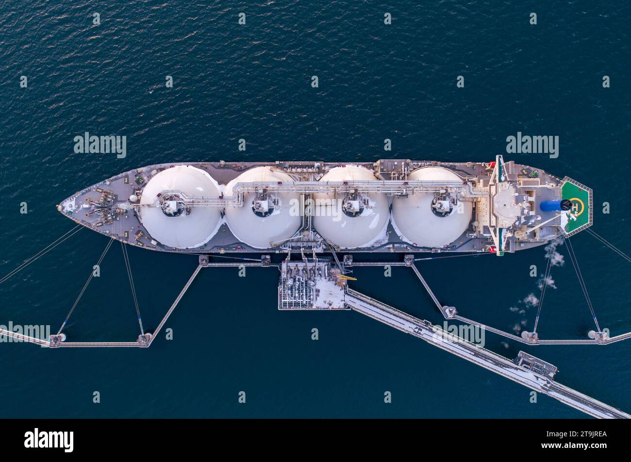 Aerial of Liquified Natural Gas LNG carrier moored to a small gas terminal. Fuel crisis. Sanctions. Top down shot. Stock Photo