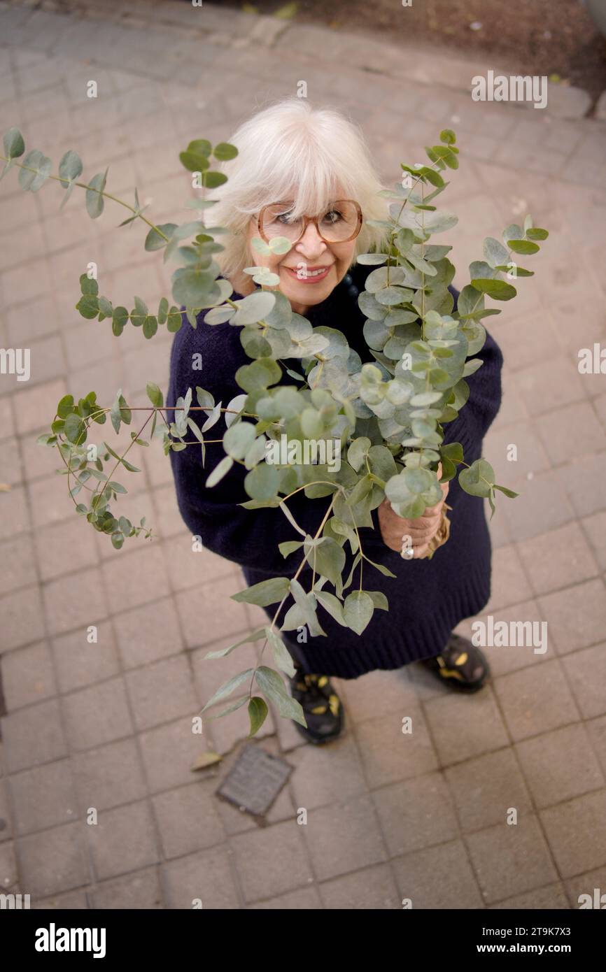 smiling older woman with bouquet of flowers seen from above Stock Photo