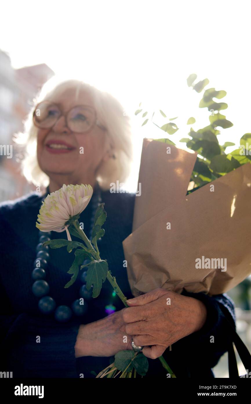 flowers in foreground held by older woman Stock Photo