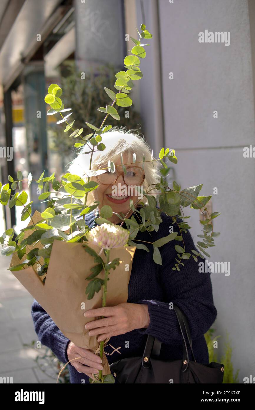 older woman with a bunch of eucalyptus outdoors Stock Photo