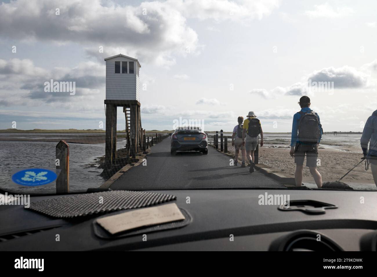 Cars and pedestrians crossing on the causeway of the Holy Island of Lindisfarne, Northumberland, UK Stock Photo
