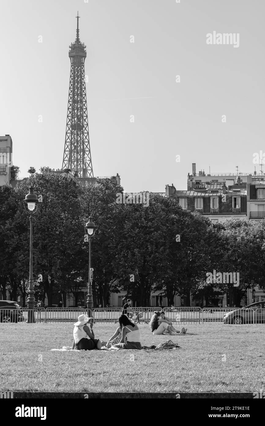 Paris, France - October 8, 2023 : Friends sitting on the grass enjoying a beautiful day and the Eiffel Tower in the background in Paris France Stock Photo