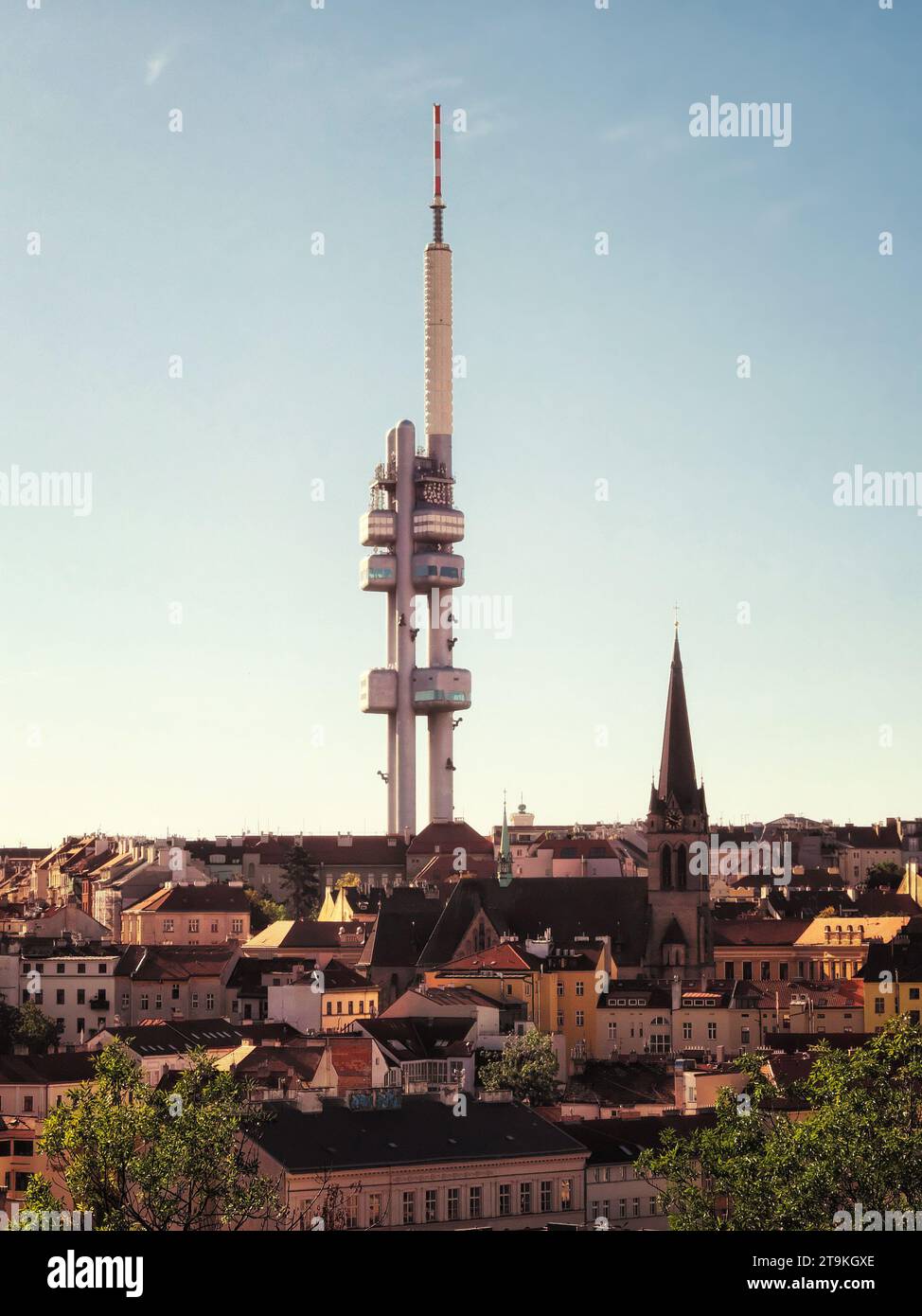 The image shows the Zizkov Television Tower in Prague, Czech Republic. It’s a tall, white structure with multiple levels and a red and white antenna o Stock Photo