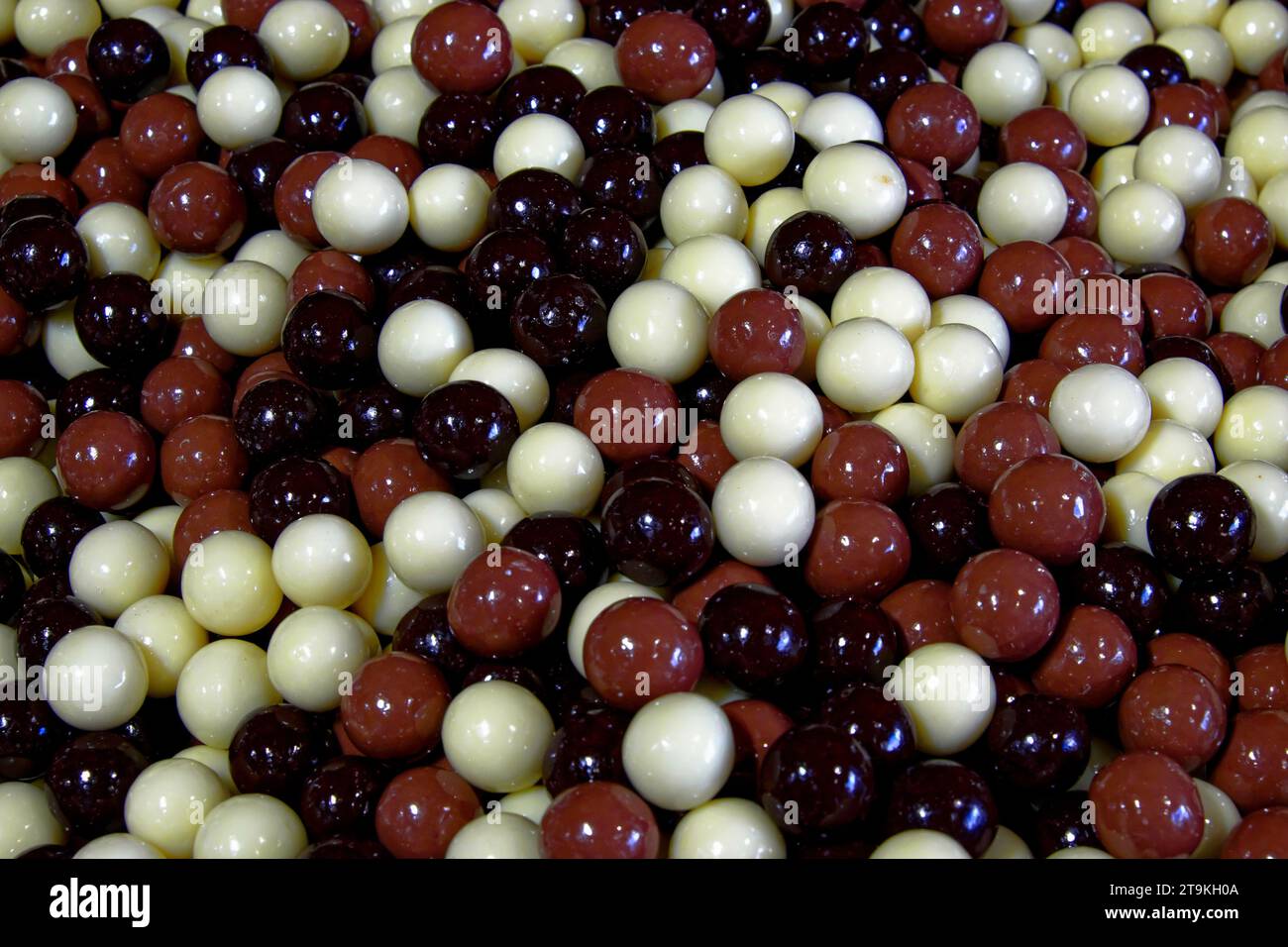 A closeup of a pile of red and white round candies. They are shiny and