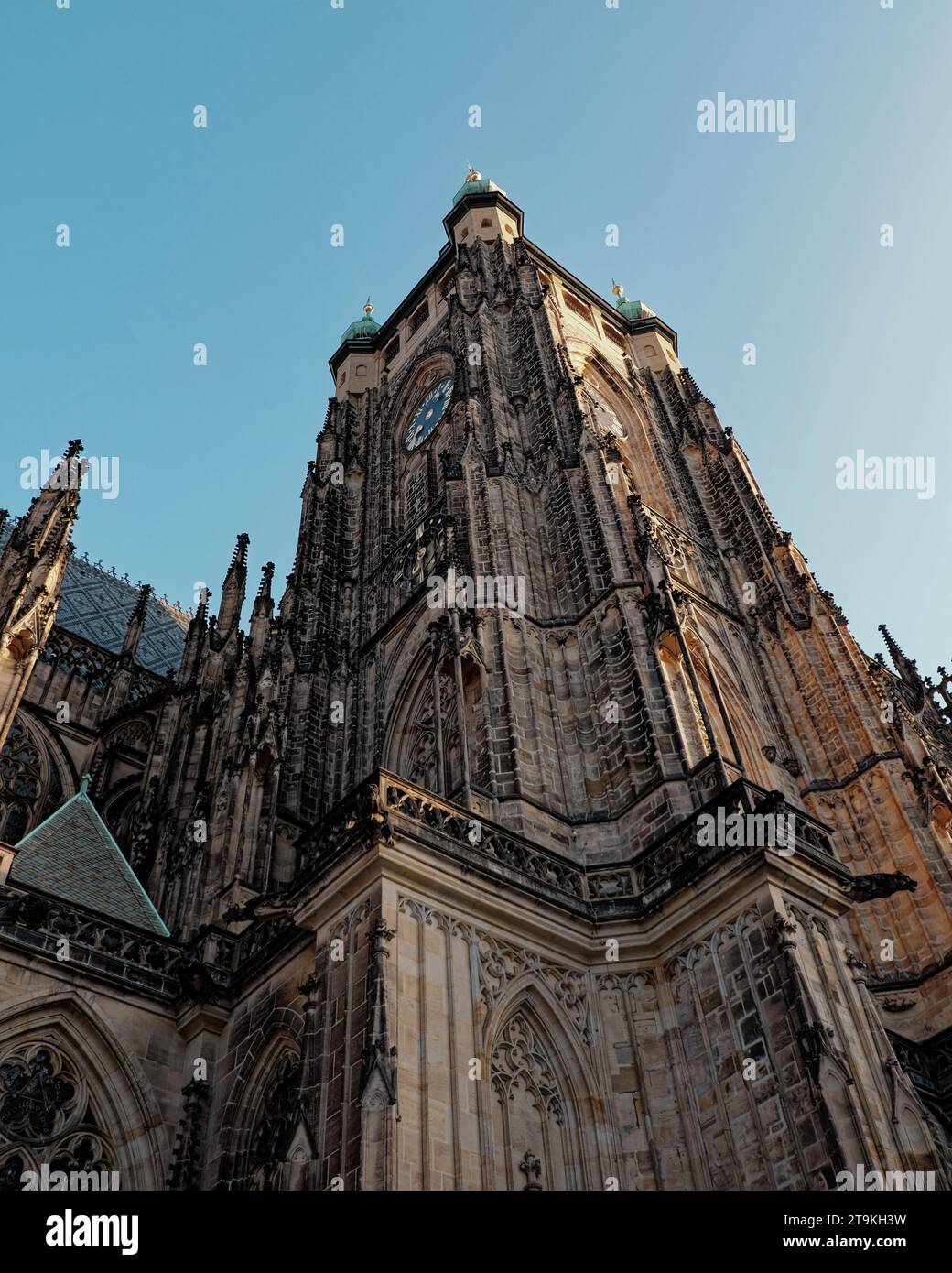 A Gothic cathedral with two towers and a clock face against a blue sky ...