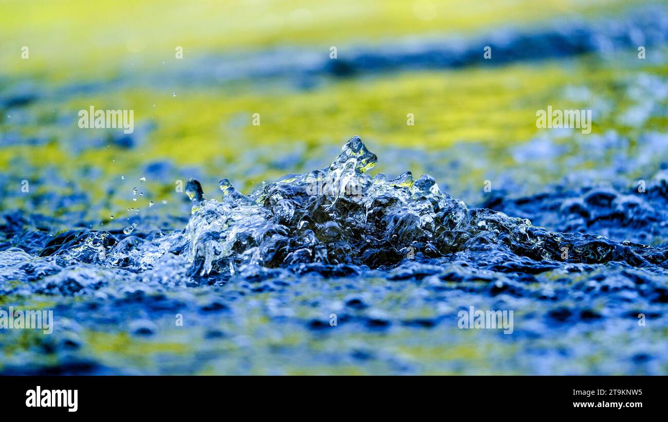 Wonderful play of colours in small drops of water in a stream in the sun. Close-up taken in sunshine on the bank. Stock Photo