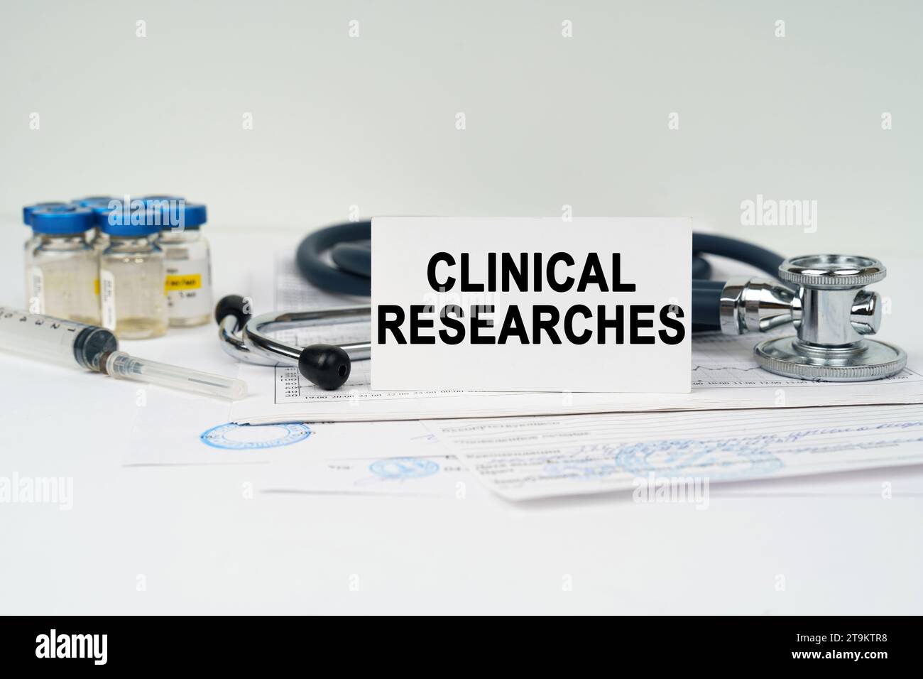 Medical concept. On the medical documents there is a stethoscope, injections, a syringe and a business card with the inscription - clinical researches Stock Photo