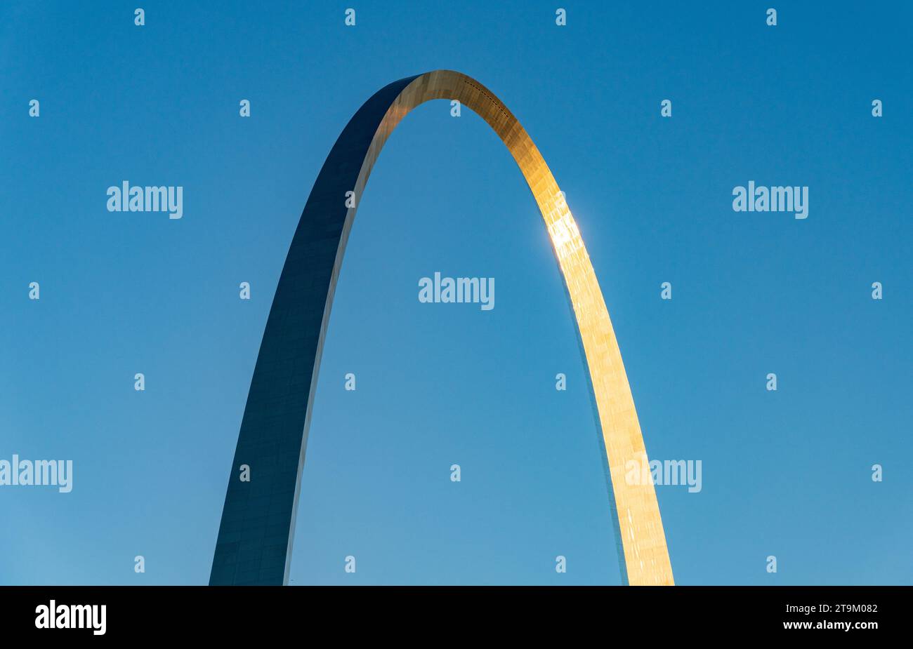 Simple abstract view of the Gateway Arch in St Louis at sunrise set against a plain blue sky Stock Photo