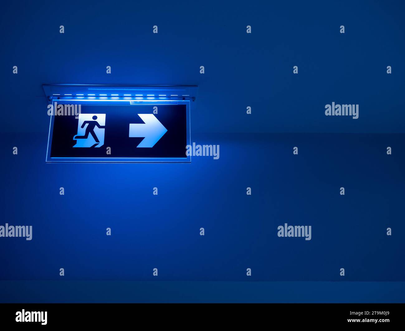 Blue tone of LED light fire escape sign hang on the ceiling in the dark