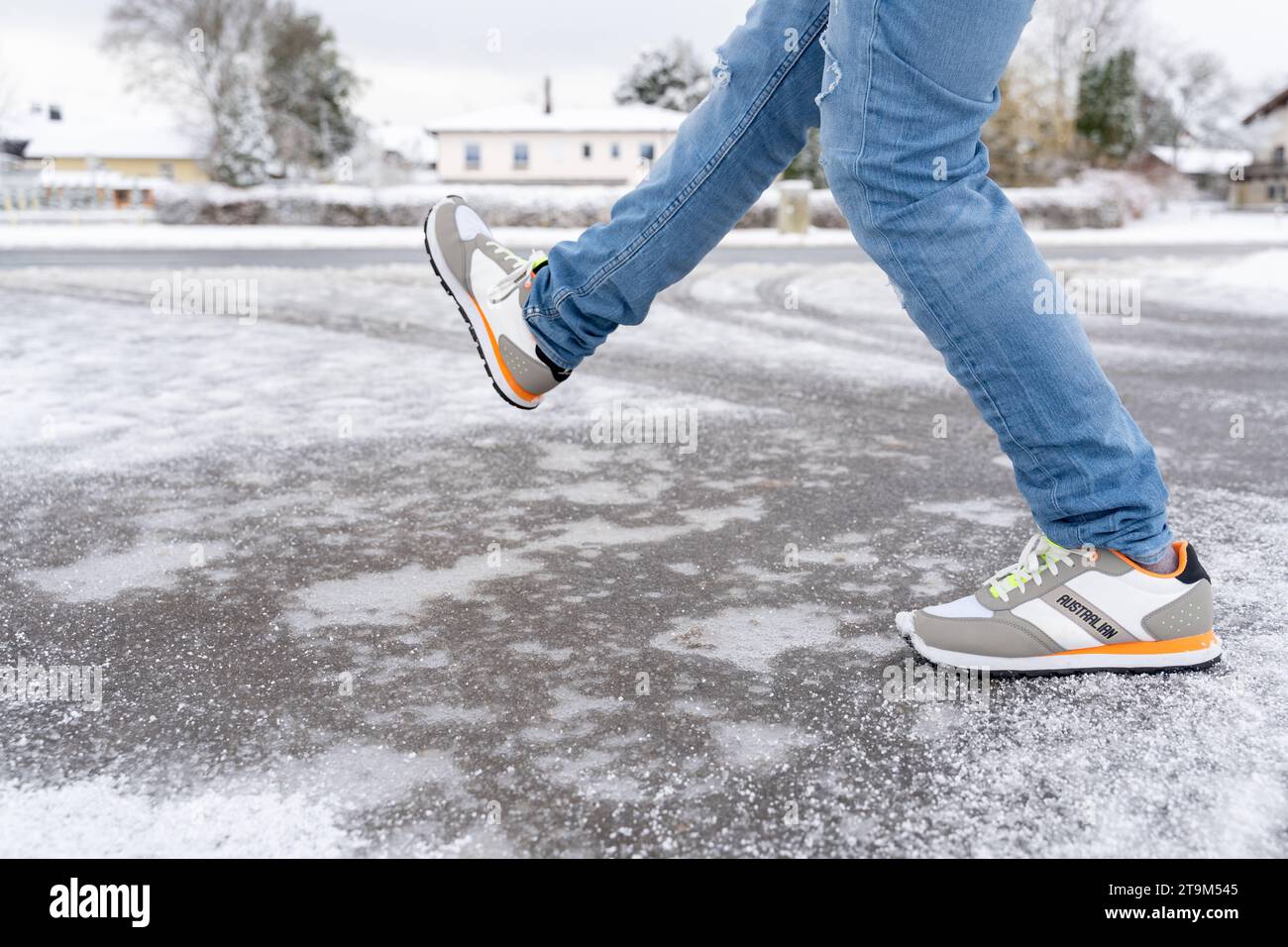 Bavaria, Germany - November 26, 2023: A man slips on a frozen snow-covered road. Danger of accidents in winter *** Ein Mann rutscht auf einer gefrorenen Schneebedeckten Straße aus. Unfallgefahr im Winter Stock Photo