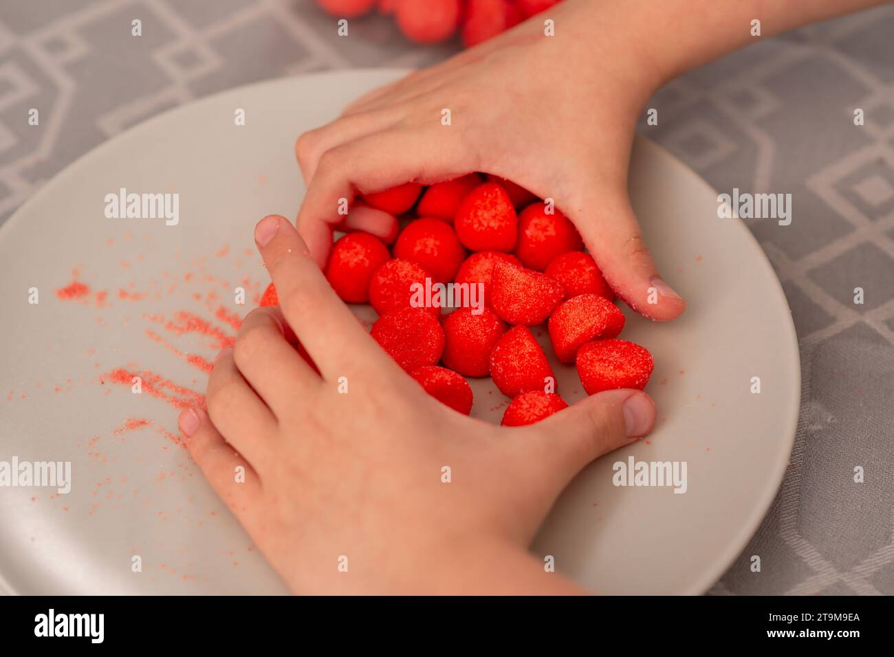 Child's playtime delight tiny hands reaching for red fruity candies on