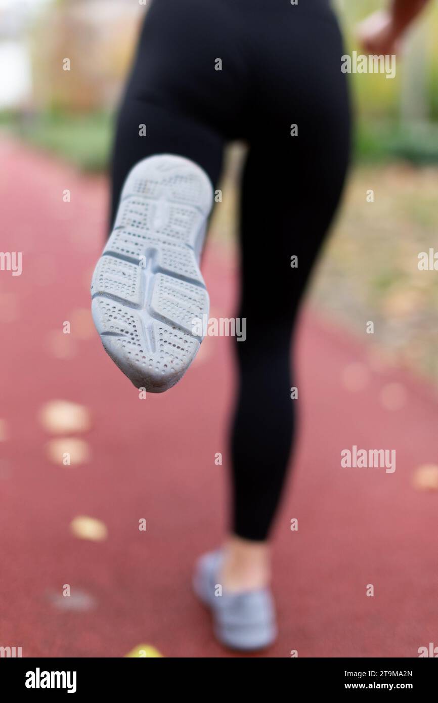 Running woman legs in sportswear on running track at autumn back view, closeup,. depth of field Stock Photo