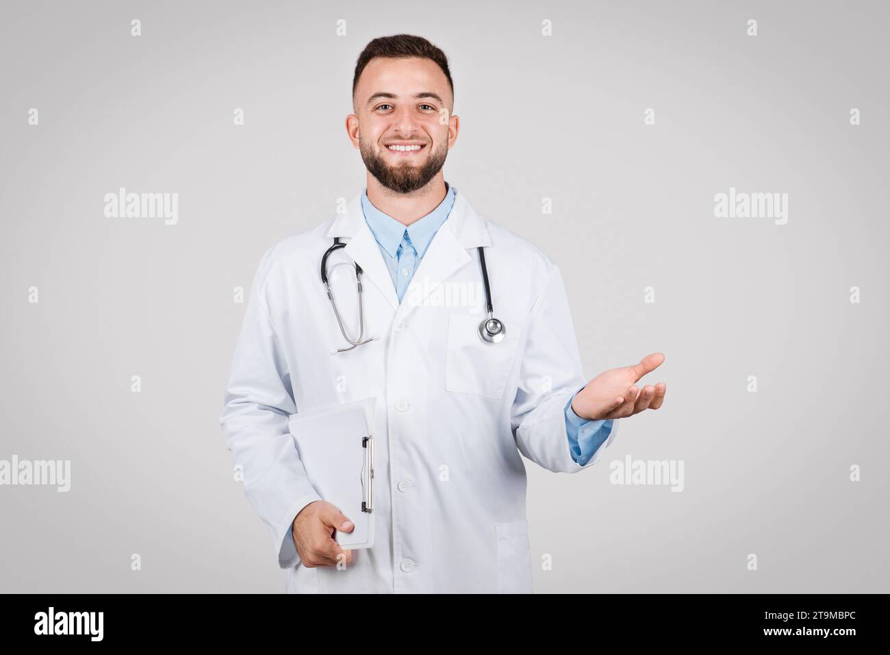 European male doctor holding clipboard and gesturing Stock Photo