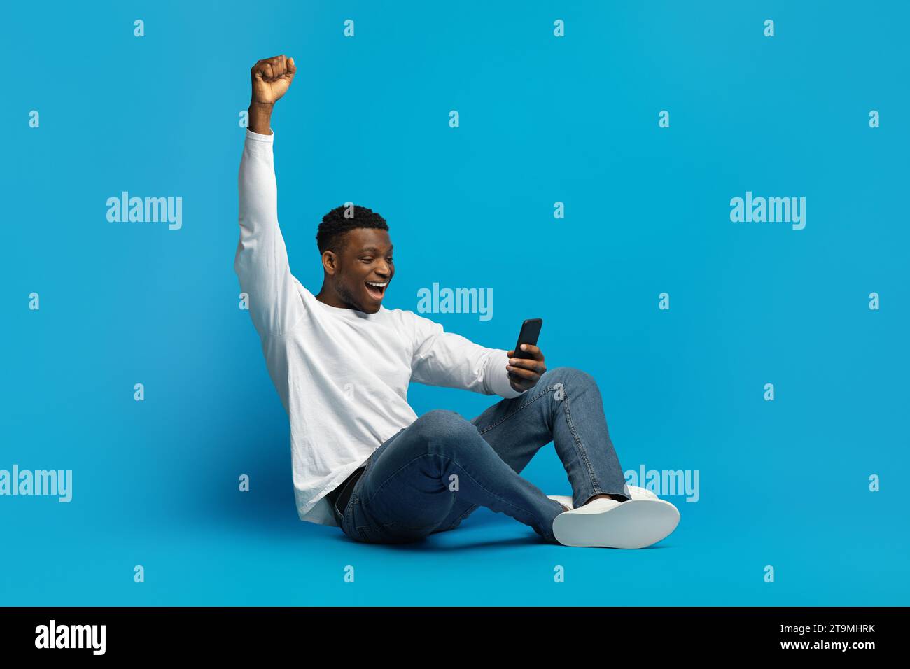 Excited Black Man Celebrating Win, Using Cellphone Stock Photo
