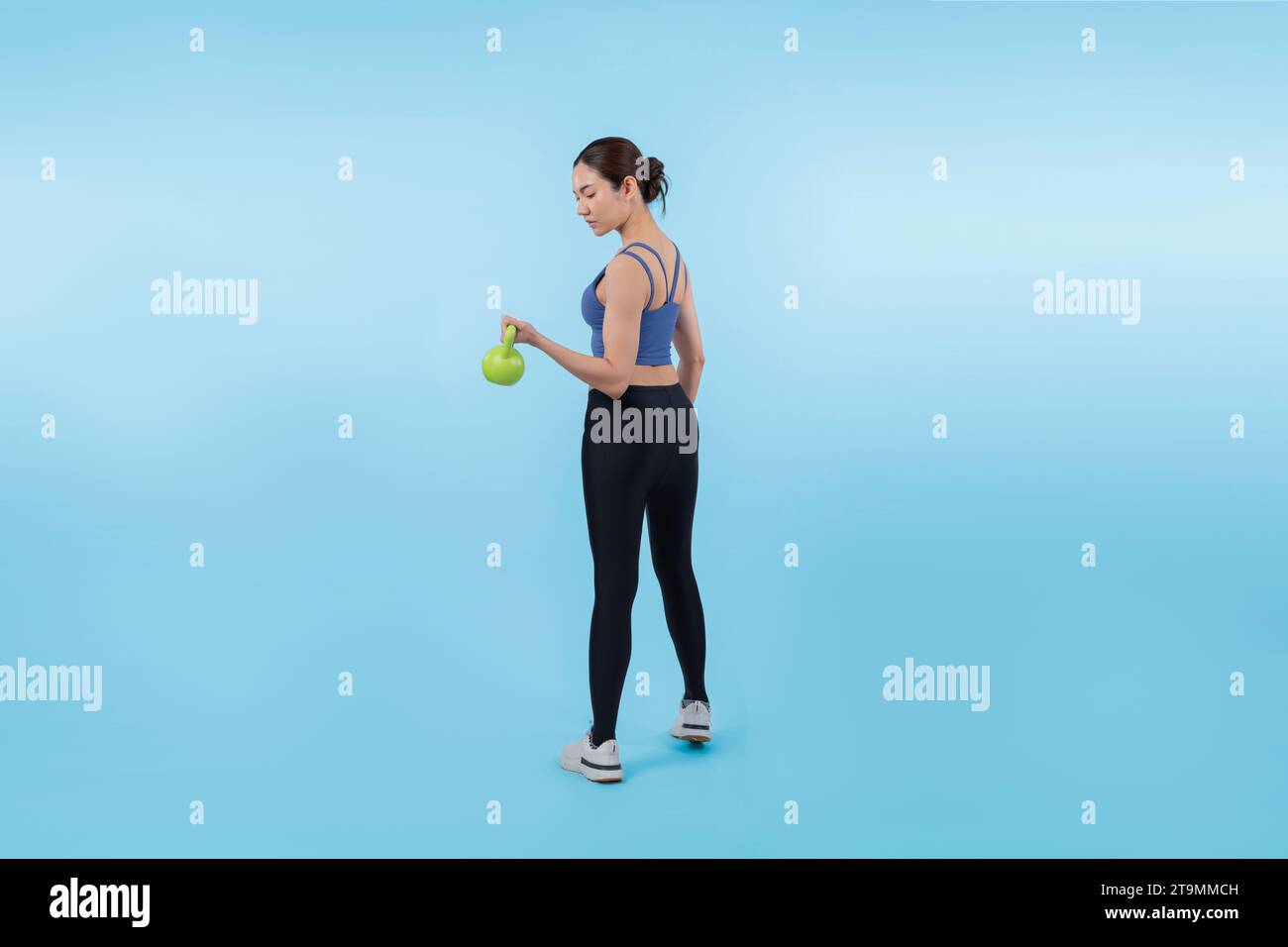 Vigorous energetic woman doing kettlebell weight lifting exercise on