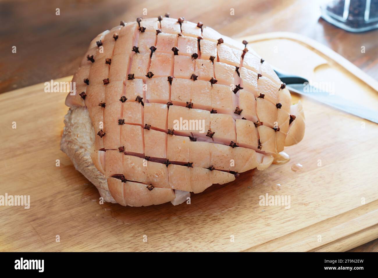 Rind of a raw roast pork cut in diamond shape and larded with cloves on a wooden kitchen board, cooking preparation for a Christmas ham, copy space, s Stock Photo
