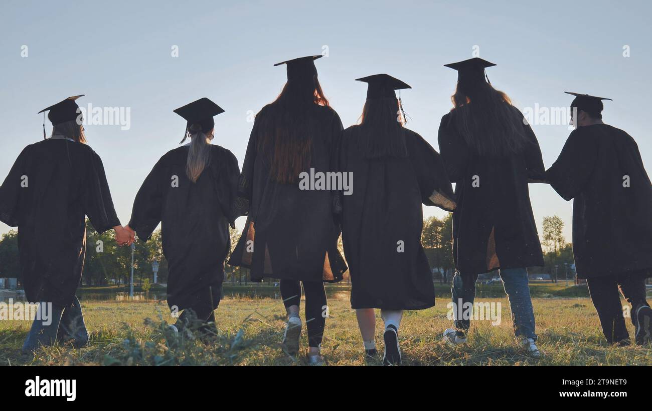 Graduate students walking through an evening meadow at sunset. Stock Photo