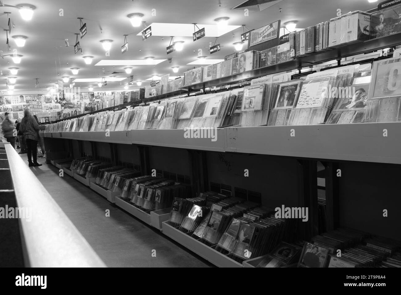 Aisle of used CDs at Amoeba Music in San Francisco, California; music shoppers in the distance at the end of the aisle; monochrome black and white. Stock Photo