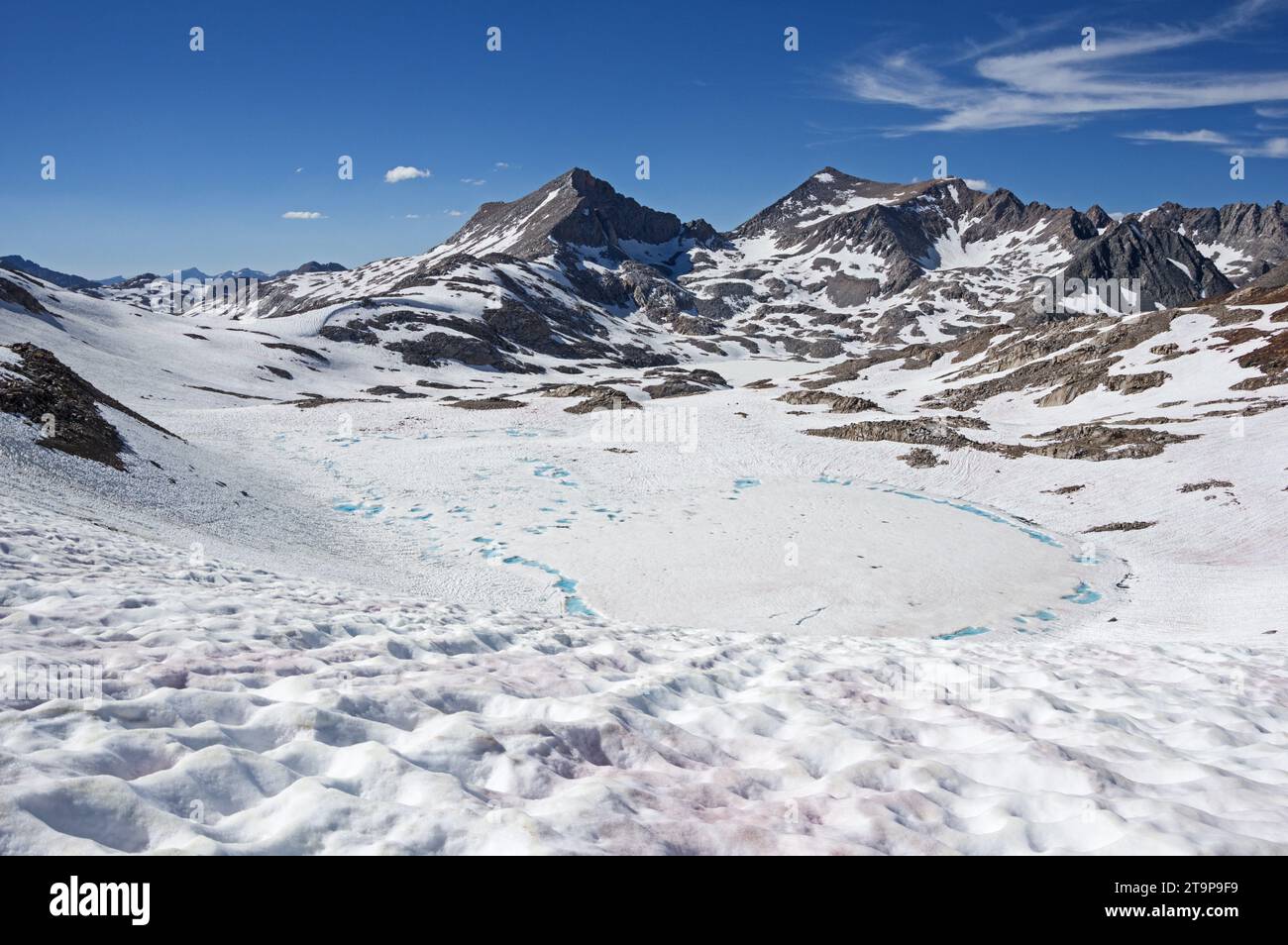 Muir Pass Mount Warlow and Mount Fiske beyond a frozen lake in Kings Canyon National Park in the Sierra Nevada Mountains of California in July of a hi Stock Photo