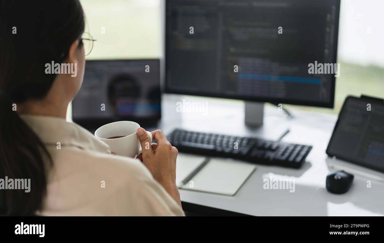 Developer programmer drinking coffee and checking code on monitor for programming to developing web. Stock Photo