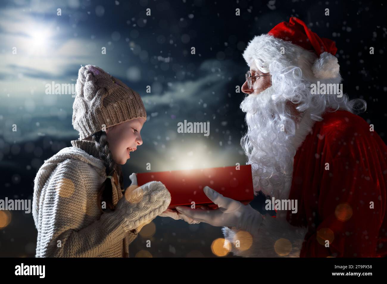 Merry Christmas and happy holidays. Cute little child girl and Santa Claus with gift. Christmas legend concept. Stock Photo