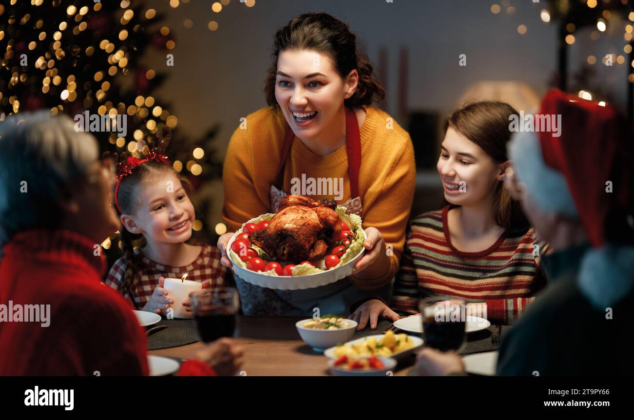 Merry Christmas! Happy family are having dinner at home. Celebration holiday and togetherness near tree. Stock Photo