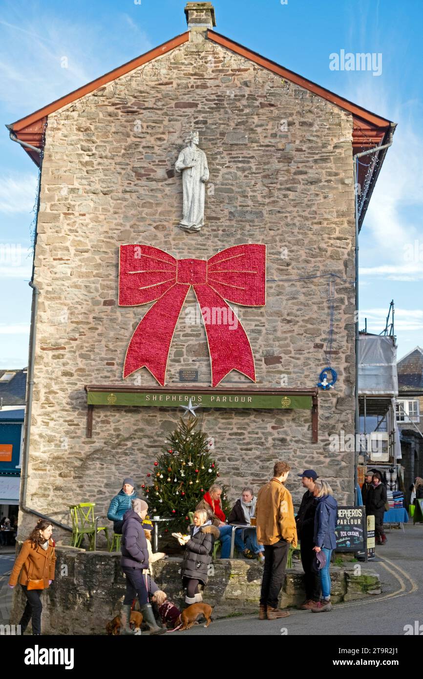 Hay-on-Wye town Hall with red bow, Christmas tree and people walking in the square during Hay Winter Festival book festival in Wales UK  KATHY DEWITT Stock Photo