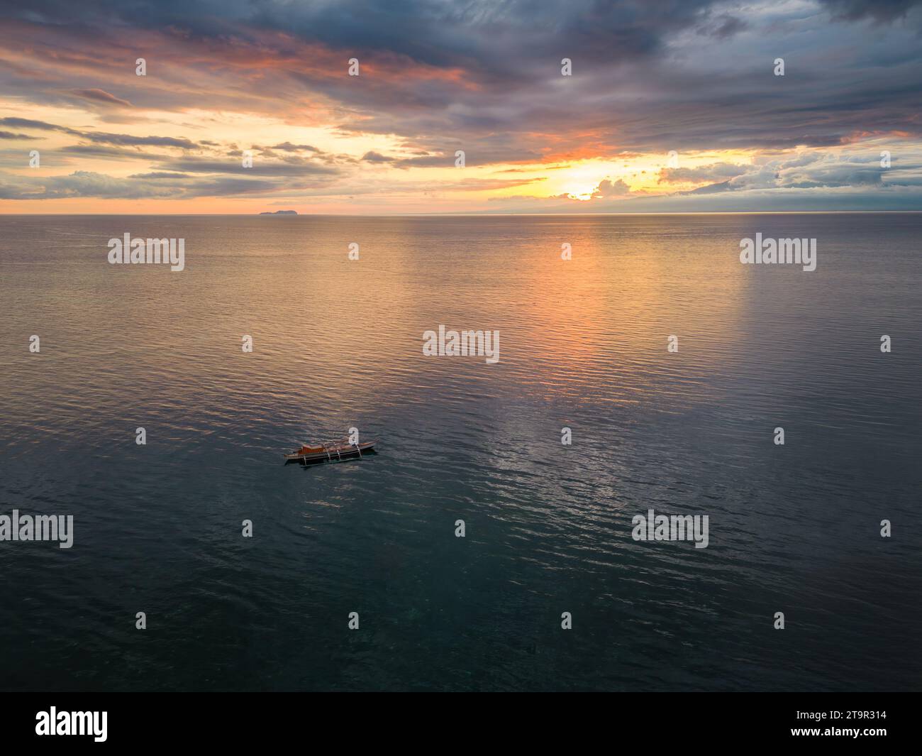 An aerial view of a boat in the sea at sunset at Siquijor, Philippines Stock Photo