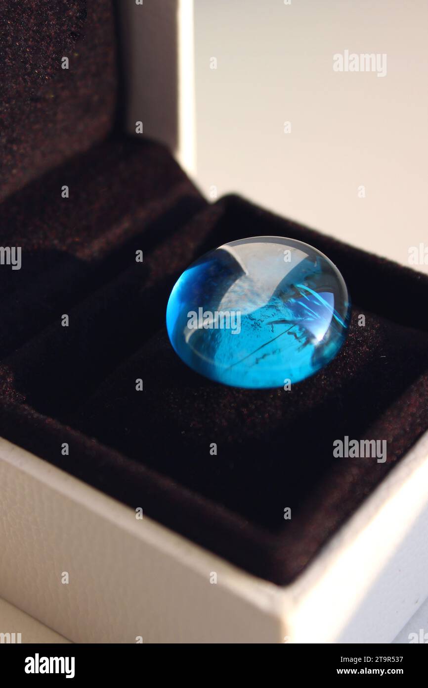 Smooth blue glass stone on a black velvet cushion in an elegant gift box detailed stock photo Stock Photo